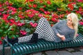 Young woman sitting outdoors by flowers in New York City, looking down, thinking Royalty Free Stock Photo