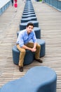 Young Man sitting on a modern style bench, relaxing and thinking Royalty Free Stock Photo