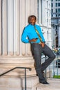 Young black businessman standing outside office, texting on cell phone Royalty Free Stock Photo