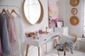 Dressing room interior with stylish makeup table, clothes and accessories