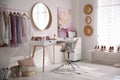 Dressing room interior with stylish makeup table, clothes and accessories