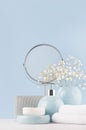 Dressing table with circle mirror, cosmetic silver accessories and white small flowers in ceramic pastel blue vase on white wood. Royalty Free Stock Photo