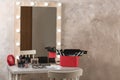 Dressing table with different makeup products and accessories in room interior Royalty Free Stock Photo