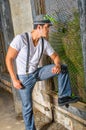 A young handsome guy is standing inside a abandoned house, looking through a screen window Royalty Free Stock Photo