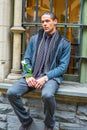 Young man sitting outdoors by window in winter, thinking Royalty Free Stock Photo