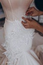 A dressmaker is perfecting her new white dress for weddings