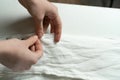 The dressmaker's hands sew white cotton fabric with a needle and thread on the work table. Close-up. Sewing Studio Royalty Free Stock Photo