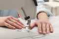 Dressmaker sewing new dress with machine in atelier, closeup