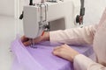 Dressmaker sewing new dress with machine in atelier, closeup