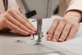 Dressmaker sewing new dress with machine in atelier, closeup