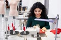 Dressmaker using professional overlock sewing machine in workshop studio. Equipment for edging, hemming or seaming