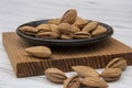 Dried almonds spilled from a dark plate onto a gray background. healthy food for raw foodists and vegetarians.