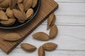 Dried almonds spilled from a dark plate onto a gray background. healthy food for raw foodists and vegetarians.