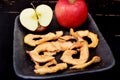 Dried apple chips and red apple on a clay dish and black background Royalty Free Stock Photo