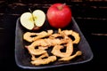 Dried apple chips and red apple on a clay dish and black background Royalty Free Stock Photo