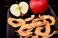 Dried apple chips and red apple on a clay dish and black background Royalty Free Stock Photo