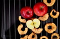Dried apple chips and red apple on a metal grill and black background Royalty Free Stock Photo