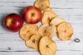 Dried apples near two fresh on a wooden background.