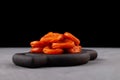 Dried apricot fruits on wooden serving plate. Healthy alternative sweets. Dark background, Selective focus, copy space