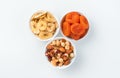 Dried apricots, dried banana and a mixture of nuts and candied fruits in three cups on a light background. Royalty Free Stock Photo