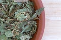 Dried bilberry leaf in a small bowl on a wood table