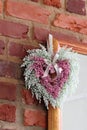 Dried blue and purple heather heart wreath hanging on mirror corner on brick wall