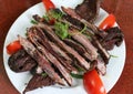 Dried buffalo meat on white dish with tomato and herbs