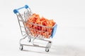 Dried carrot chips in a toy grocery cart on a white background. Organic natural food. Concept vegan shopping