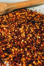 Dried chili flakes on wooden background. Close up view of crushed red cayenne pepper. Top view of red chili flakes as texture. Royalty Free Stock Photo