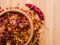 Dried chili pepper flakes in wooden bowl on the wooden table. Dried and crushed fruits of Capsicum frutescens, used as Royalty Free Stock Photo
