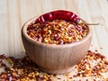 Dried chili pepper flakes in wooden bowl on the wooden table. Dried and crushed fruits of Capsicum frutescens, used as Royalty Free Stock Photo