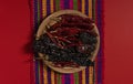 Dried Chilis on wood dish Red background mexican tablecloth