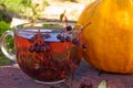 Dried chokeberry fruit tea in a transparent cup. Transparent cup of choke berry tea next to an autumn pumpkin on a