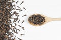 Dried cloves in wooden spoon on white rustic table