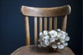 Dried dandelion in a small glass bottle on wooden Viennese chair near a dark blue wall