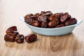 Dried dates in blue bowl, dates on wooden table