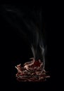 Dried deer meat. Thin planks with curled edges, shaped like a pyramid, and a plume of smoke, on a black vertically.