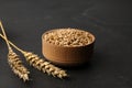 Dried ears of wheat and grains in wooden bowl on black table Royalty Free Stock Photo