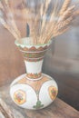 Dried ears of wheat in vintage style vase on wooden background. Spikelets of wheat in ceramic vase Royalty Free Stock Photo