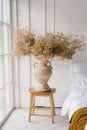 Dried flowers in a classic vase on the bedside table with pillows near the French window Royalty Free Stock Photo