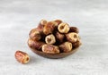 Dried fruit sagay dates in a wooden bowl on a white background.