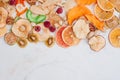 Dried fruit and vegetable chips, candied pumpkin slices, nuts and seeds on white marble background with copy space Royalty Free Stock Photo