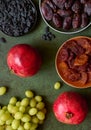 Dried fruits, apricots, raisins, dates, red pomegranates and grape close-up on a green background Royalty Free Stock Photo