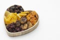 Dried fruits mix, in wooden heart shape dbox isolated on white background. Top view of various dried fruits figs, apricots, mango