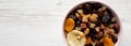 Dried fruits and nuts in a pink bowl over white wooden background, overhead view. Top view, from above, flat lay. Space for text Royalty Free Stock Photo