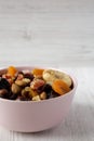 Dried fruits and nuts in a pink bowl over white wooden background, side view. Copy space Royalty Free Stock Photo