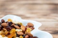 Dried fruits in white plate on wooden table, copy space for text. Mix of different varieties of nuts and berries, vitamins Royalty Free Stock Photo