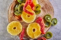 Dried fruits: Yellow candied pineapple rings, red papaya and green kiwi on a wooden board Royalty Free Stock Photo