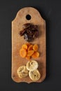 Dried fruitson rustic wooden board on black surface, top view. Overhead, from above, flat lay Royalty Free Stock Photo