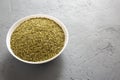 Dried Green Greek Oregano Spice in a white bowl on a gray surface, low angle view. Copy space Royalty Free Stock Photo